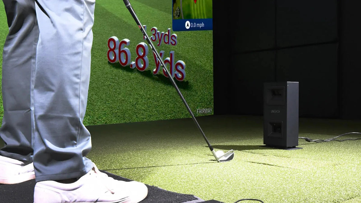 How accurate are golf simulators: a golfer beside a Uneekor EYE MINI LITE launch monitor, with shot distance on the simulator screen